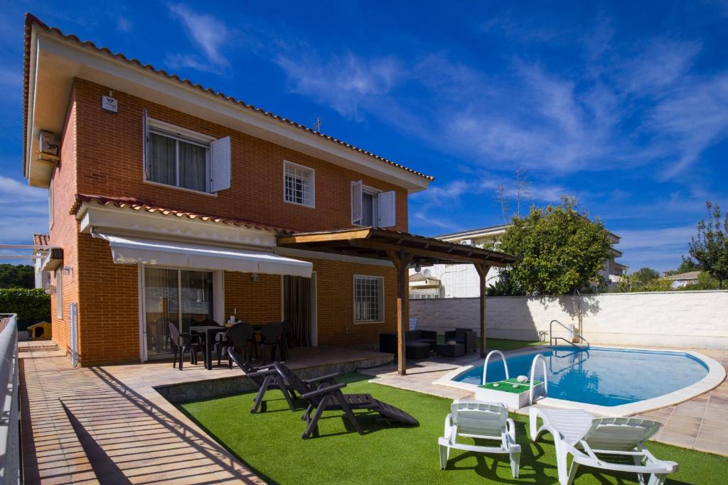 un patio trasero con piscina y una casa en Villa PLUMA Planet Costa Dorada - ONLY FAMILIES en Salou