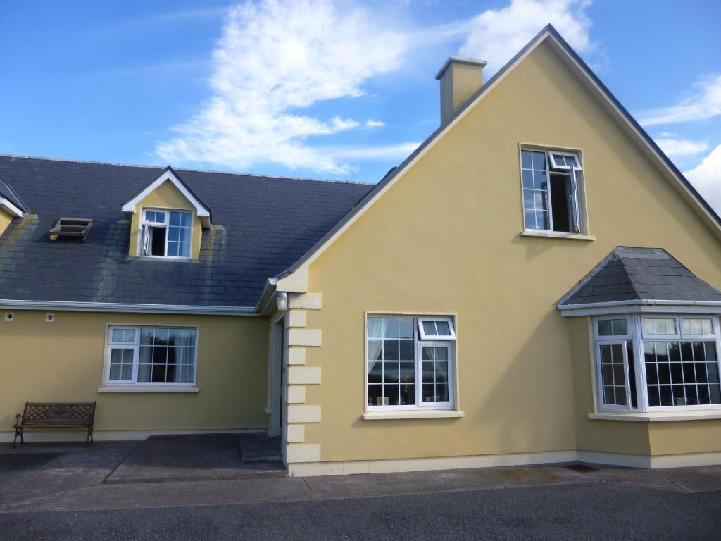 a yellow house with white windows and a roof at Ferryview B&B in Cahersiveen