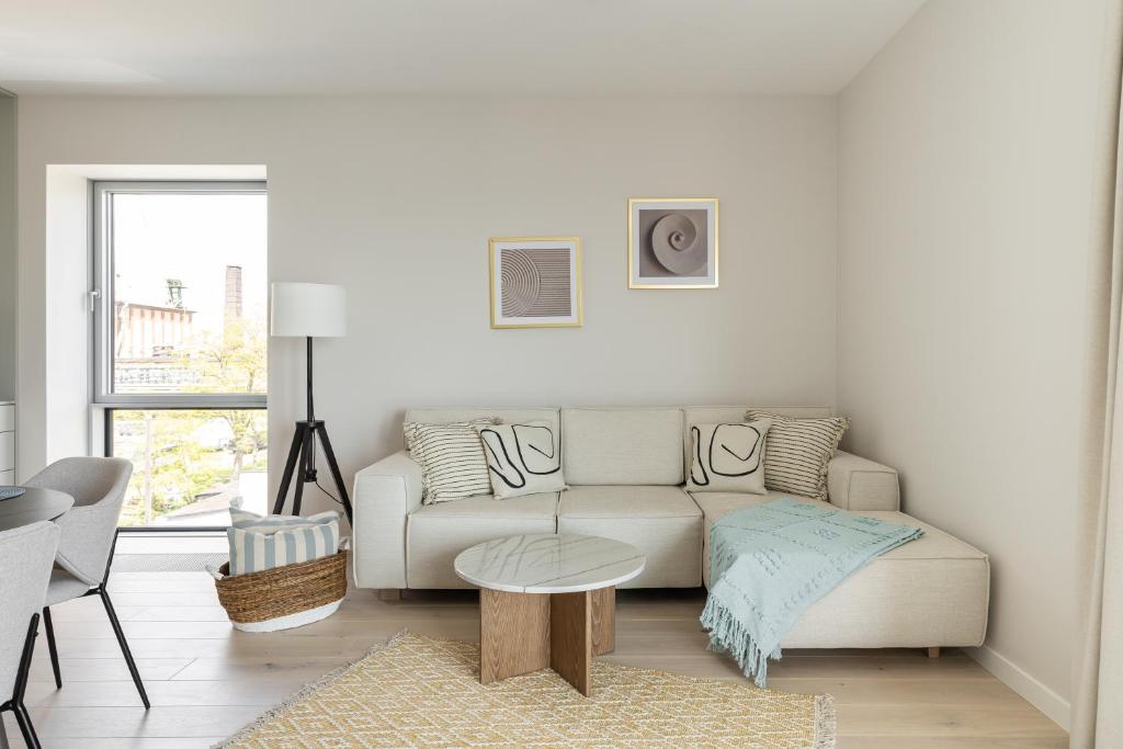 ein weißes Wohnzimmer mit einem Sofa und einem Tisch in der Unterkunft Lion Apartments - Gdynia Yacht Park with Sea View in Gdynia