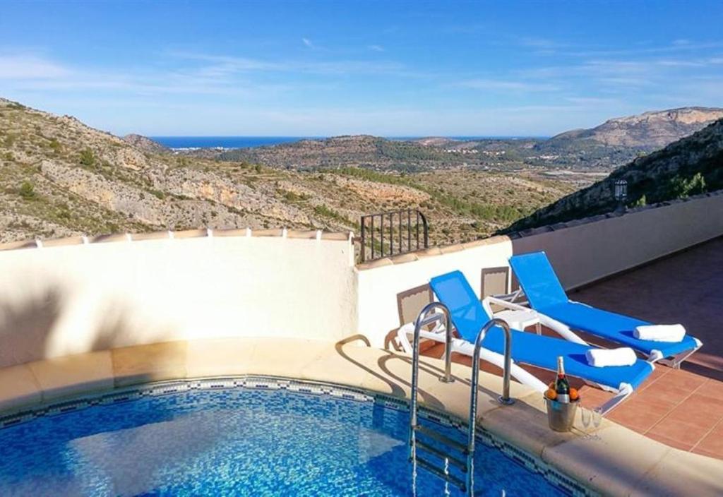 uma piscina com cadeiras azuis e vista para o oceano em Nice villa beautiful view em Pedreguer