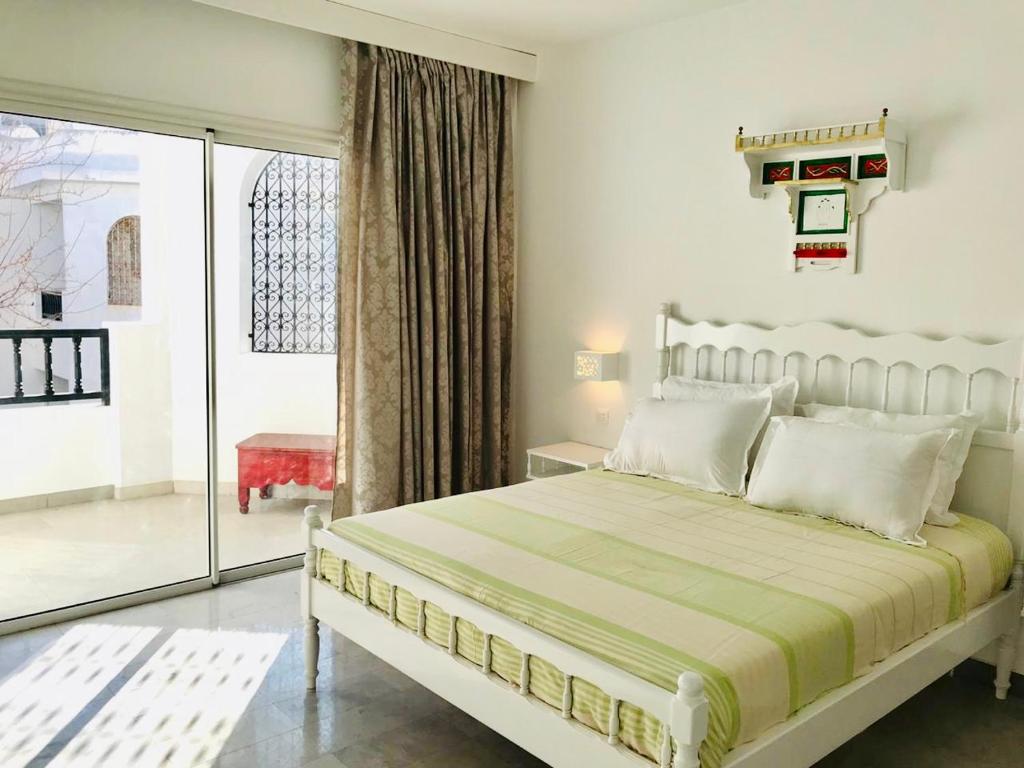 um quarto branco com uma cama e uma porta de vidro deslizante em Résidence Neffati em Hammamet