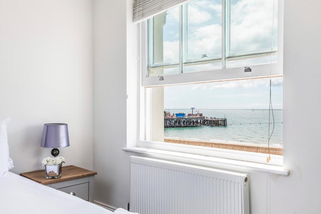 1 dormitorio con ventana y vistas al océano en Ashbys Seafront 2 Bedroom Apartment en Portsmouth
