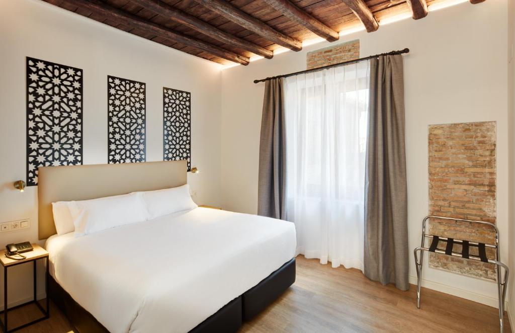 a bedroom with a white bed and a window at Sercotel Granada Suites in Granada