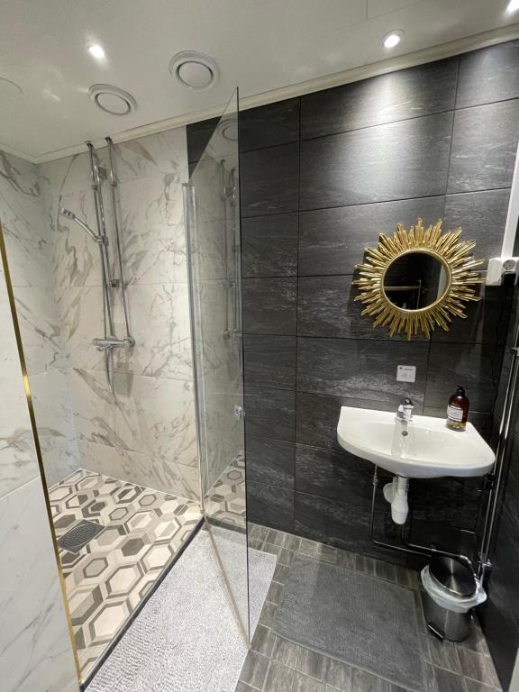 uma casa de banho com um lavatório e um chuveiro com um espelho. em Wherever Mini Hostel em Rovaniemi