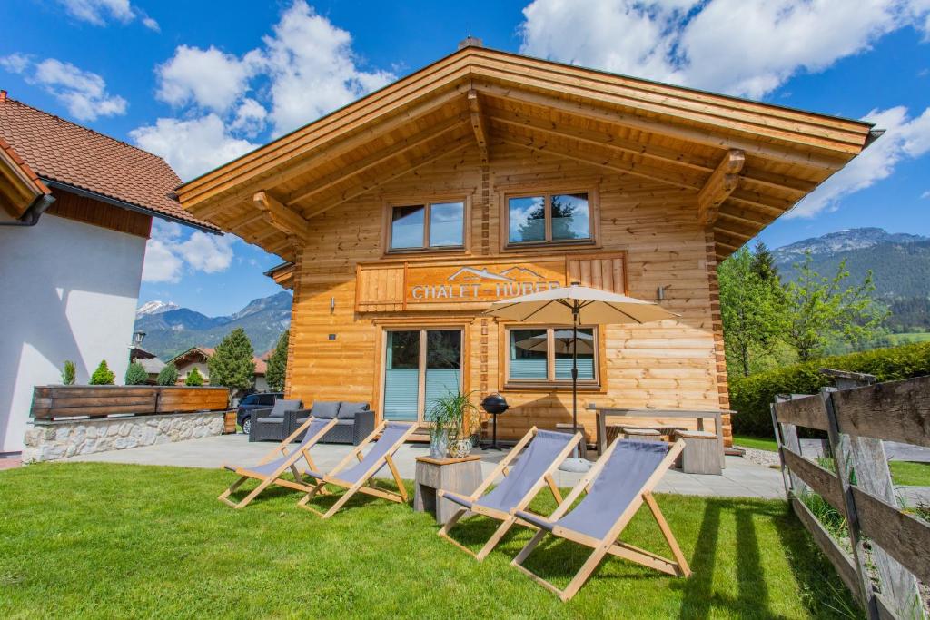 a log cabin with chairs and an umbrella at Chalet Huber by Alpenidyll Apartments in Aich