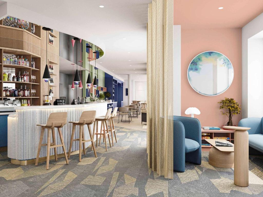 - un hall avec un bar avec des tabourets et des chaises dans l'établissement ibis Styles Paris Poissy, à Poissy