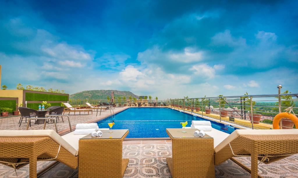 a pool on top of a building with chairs and tables at Clarion Inn Jaipur in Jaipur