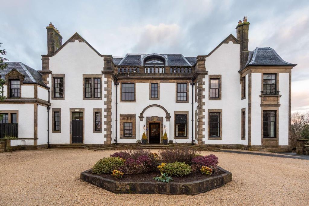 a large white house with some flowers in front of it at Gleddoch Golf & Spa Resort in Langbank