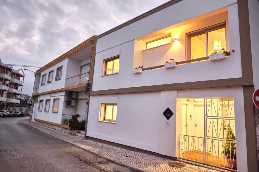 a white building with windows on the side of a street at Casas do Portinho in Marinha Grande