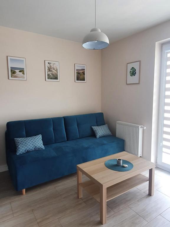 a blue couch in a living room with a table at Morze i Las in Dziwnówek