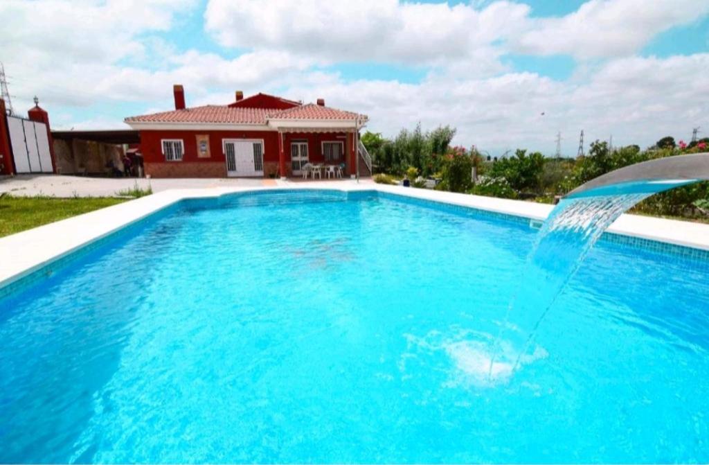 a swimming pool with a fountain in front of a house at Casa campo Ramos in Cártama