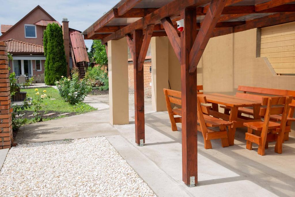 uma pérgola de madeira com uma mesa de madeira e cadeiras num pátio em VillaNána em Tiszanána