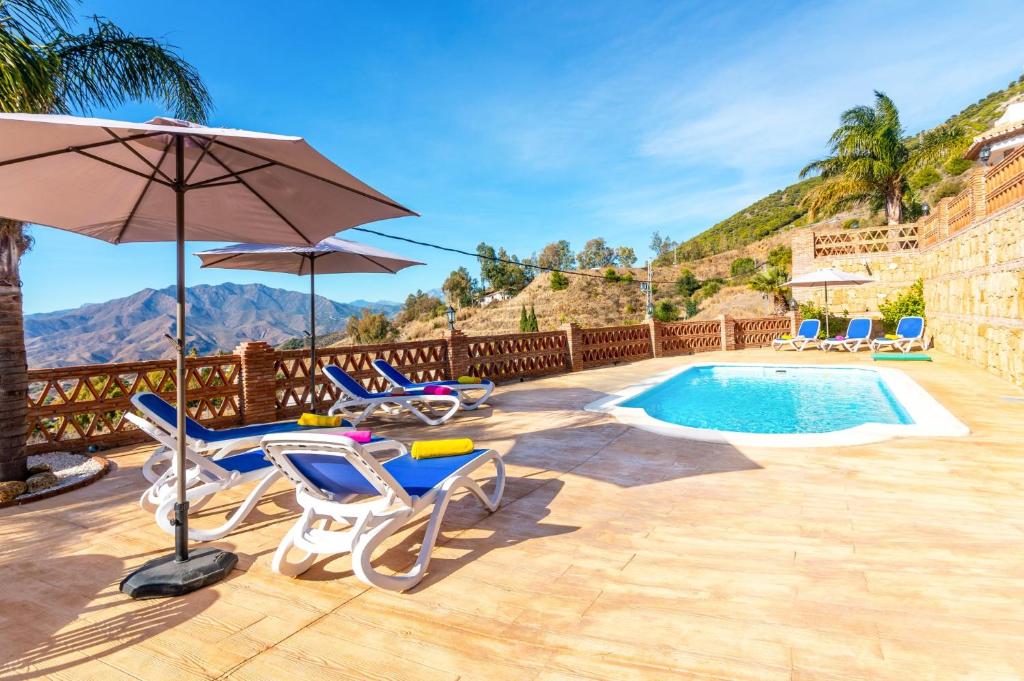 patio z krzesłami, parasolem i basenem w obiekcie Villa Biznaga by Villa Plus w mieście Mijas