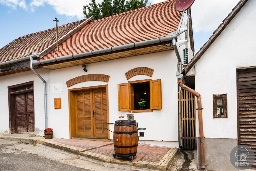 Biały dom z drewnianymi drzwiami i beczką w obiekcie Szeparé pinceház szállás Villány központi részén. w mieście Villány