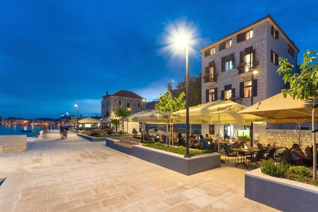 a patio with tables and umbrellas next to a building at Luxury Apartments Perko in Kaštela
