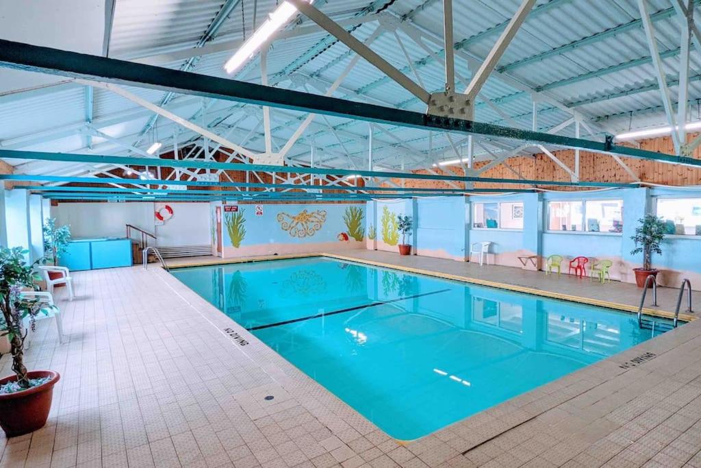 una grande piscina con acqua blu in un edificio di Immaculate Gower Getaway with Pool & Facilities a Swansea