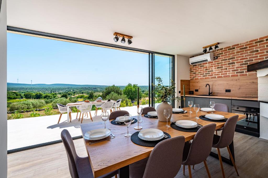 a dining room with a table and a large window at Villa Matea - heated pool, peace, view in Pridraga