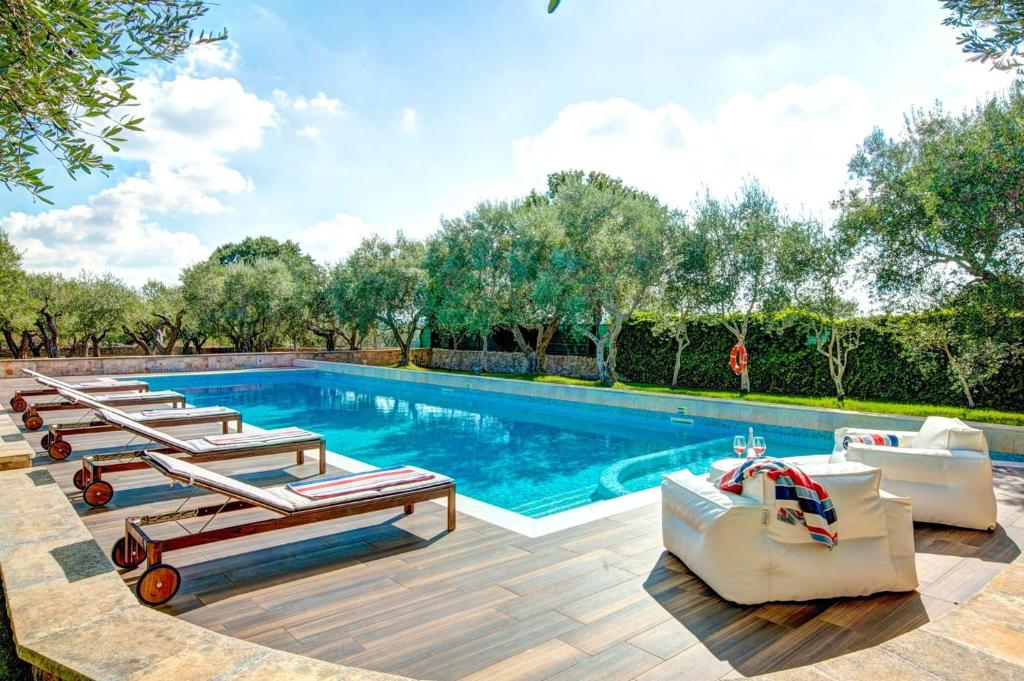 une piscine avec plusieurs chaises longues et un bassin dans l'établissement Villa Trulli Carolina by Villa Plus, à Noci