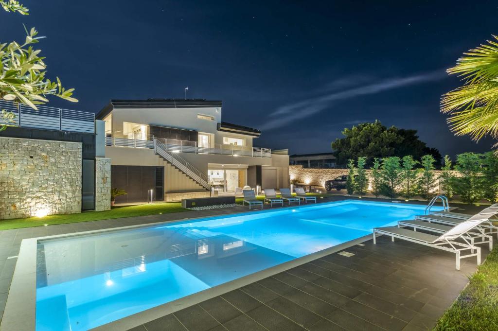 a swimming pool in front of a house at night at Villa Campanella by Villa Plus in Noci