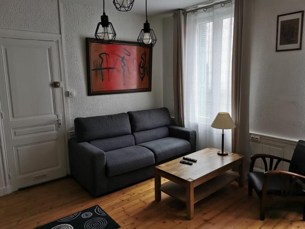 een woonkamer met een bank en een tafel bij Appartement de charme in Honfleur