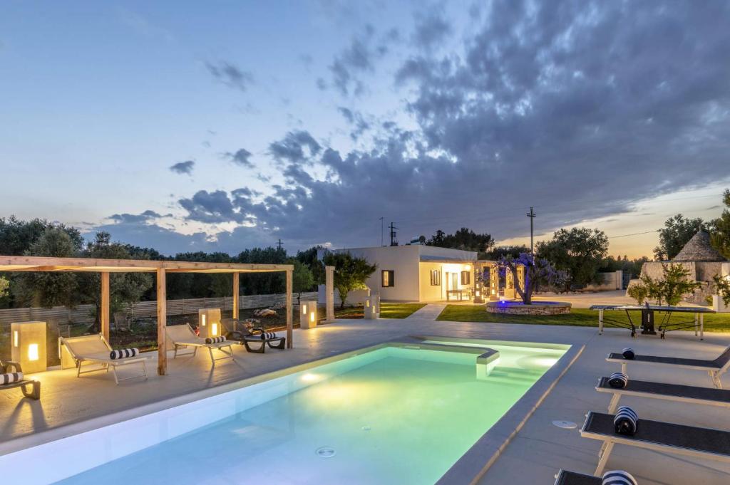 une piscine dans une cour avec des chaises et une maison dans l'établissement Villa Trullo Lofino by Villa Plus, à Carovigno