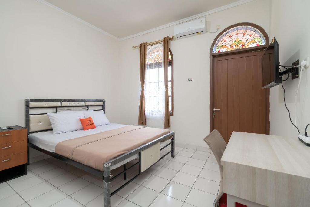 a bedroom with a bed with an orange pillow on it at KoolKost Syariah @ Cempaka Putih (Minimum Stay 6 Nights) in Jakarta