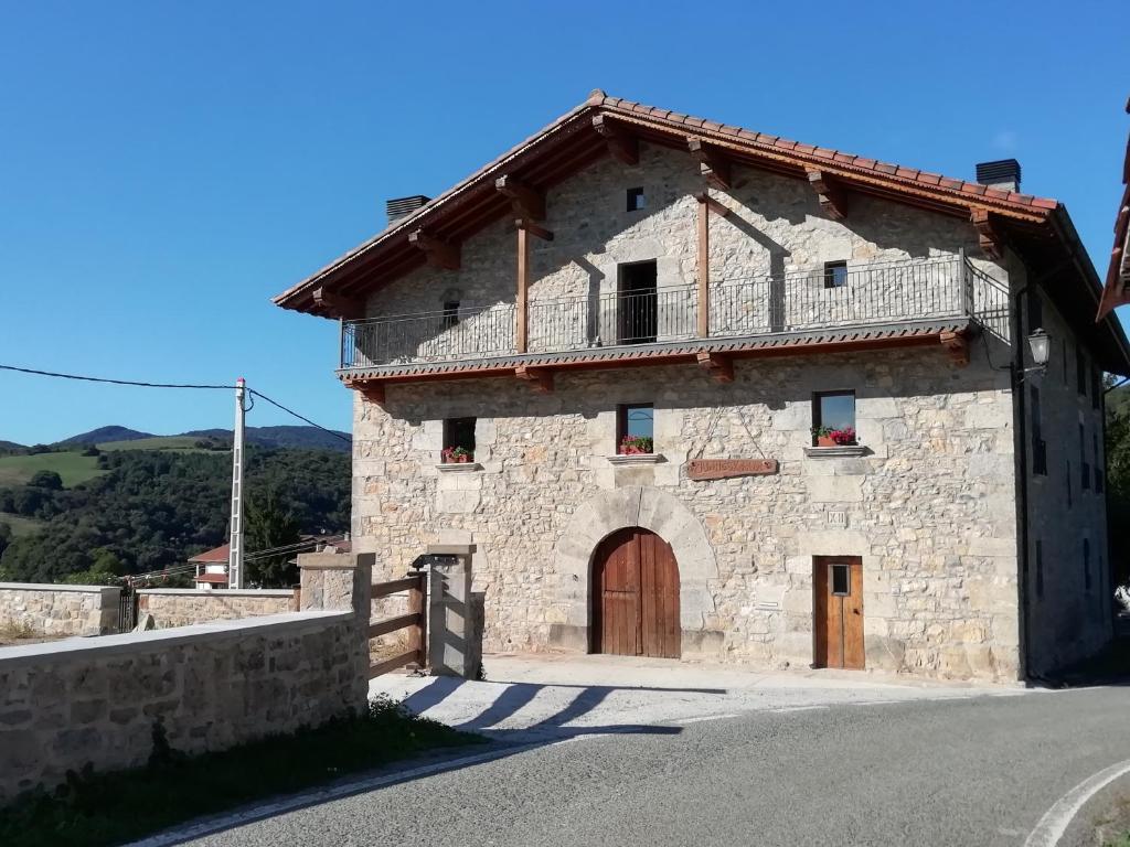 una vieja casa de piedra al lado de una carretera en CASA RURAL JUANGOXENEA en Yaben