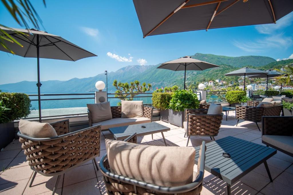 a patio with tables and chairs and a view of the mountains at Hotel la Meridiana, Lake & SPA in Ascona