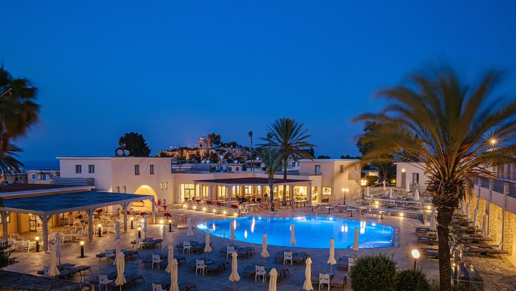 a resort with a large swimming pool at night at Louis St. Elias Resort & Waterpark in Protaras