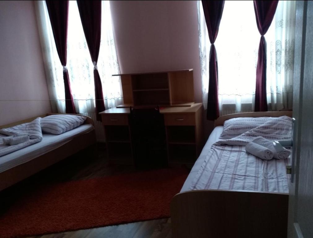 a bedroom with two beds and a desk and windows at NENSI in Prokuplje