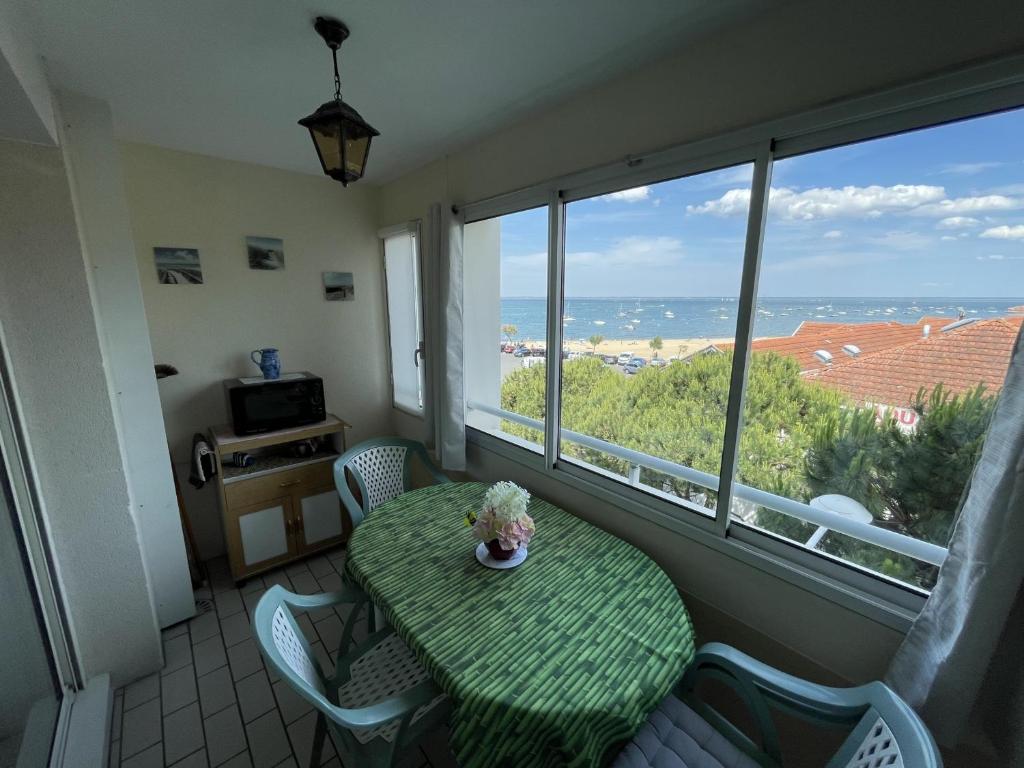 une table et des chaises dans une pièce avec une grande fenêtre dans l'établissement Bel appartement T2 à deux pas des plages, avec parking et garage - FR-1-474-212, à Arcachon