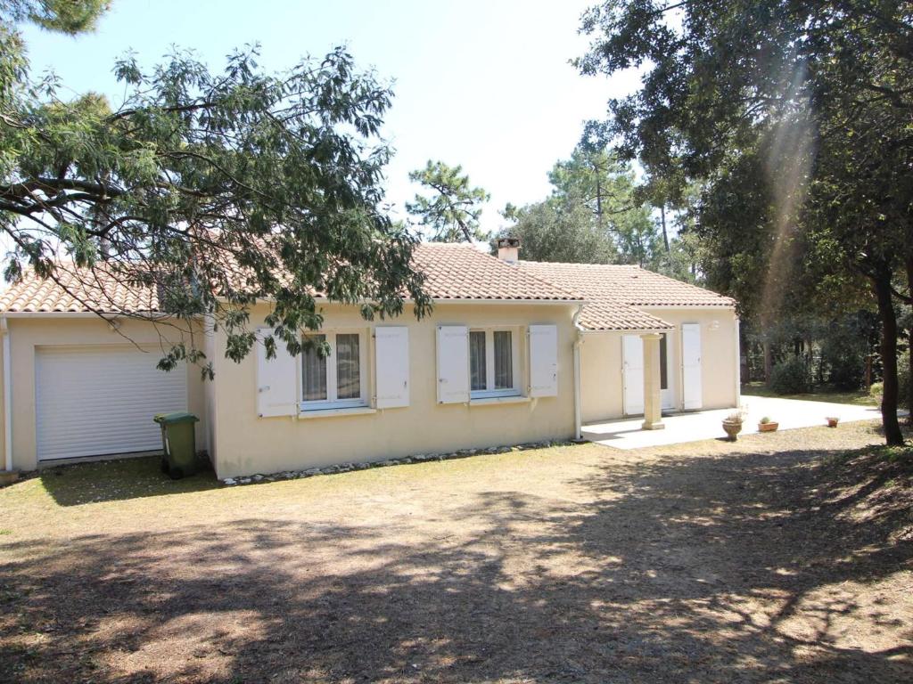 une maison blanche avec un garage et une allée dans l'établissement Maison avec grand jardin clos, 6 couchages, proche forêt domaniale - Saint-Georges-d'Oléron - FR-1-246A-131, à Saint-Georges-dʼOléron