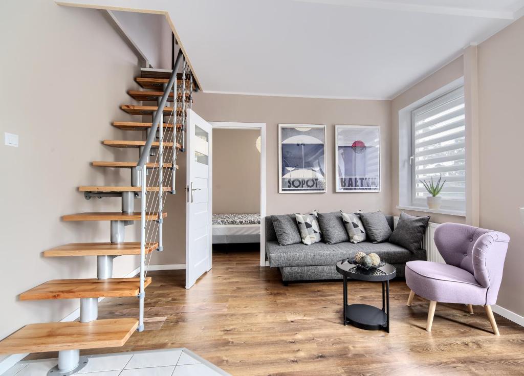 a living room with a staircase and a couch at Apartament Kajuta - NoclegiSopot in Sopot