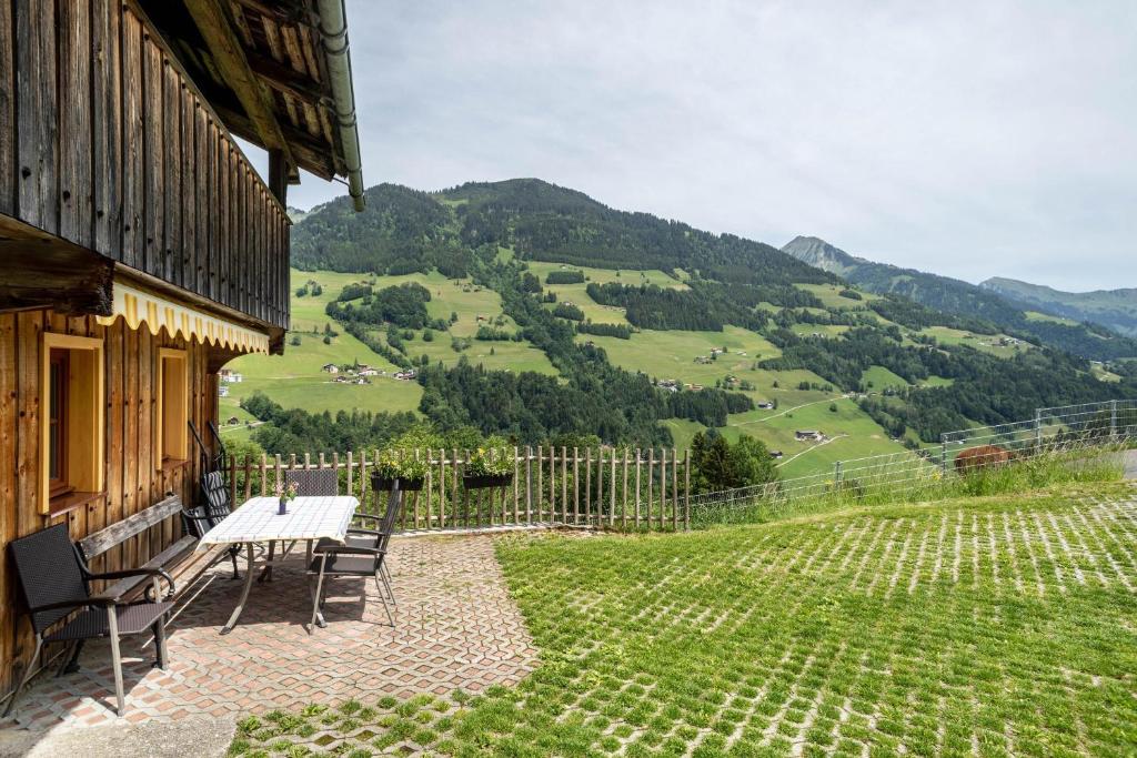 a table and chairs on a patio with a view of a hill at Knusperhäuschen Höfen-hüsle in Raggal