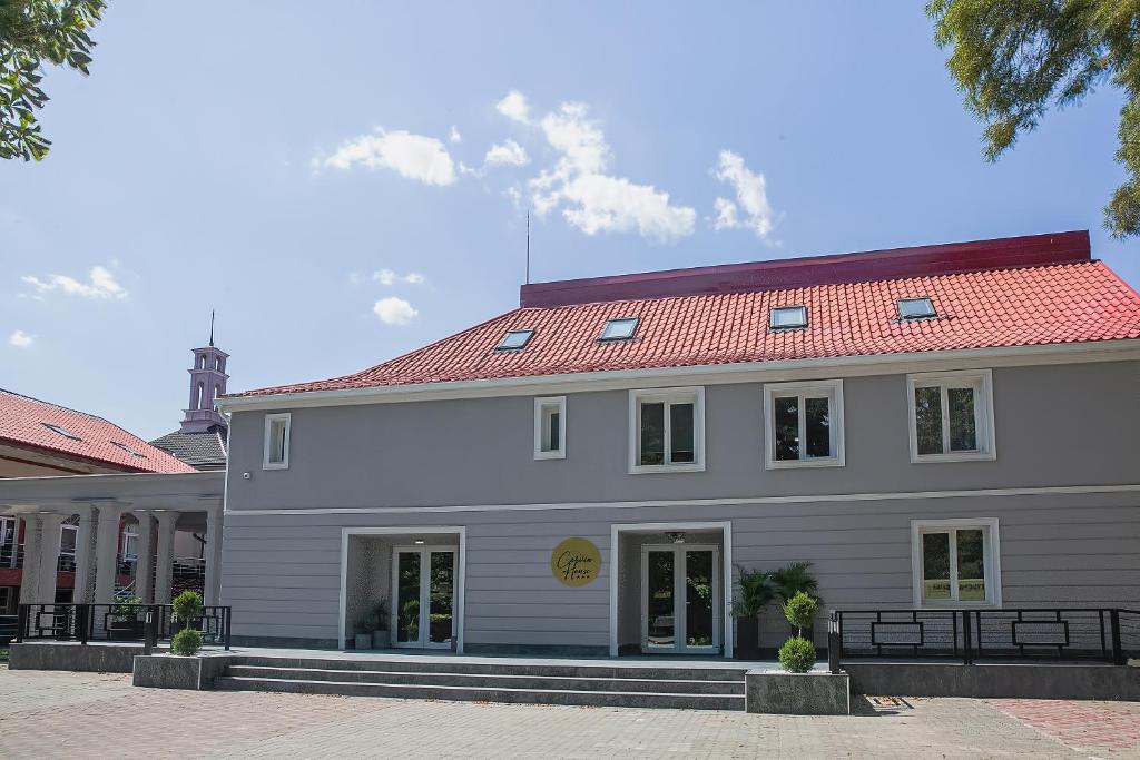 duży biały budynek z czerwonym dachem w obiekcie CORVIN HOUSE w mieście Hunedoara