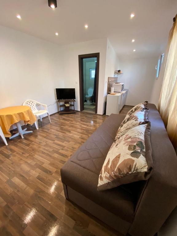 a living room with a couch and a wooden floor at Apartmani LALA 2 Canj in Čanj