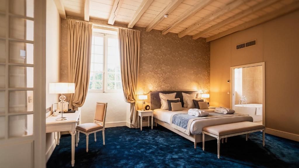 a bedroom with a bed and a desk and a window at L'Abbaye De Villeneuve in Les Sorinières