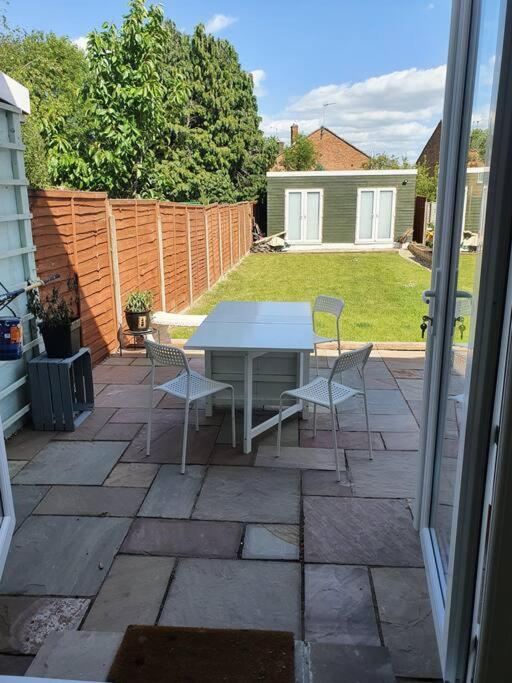 a patio with a table and chairs on a yard at Lovely 3 bedroom house with parking near airport in Luton