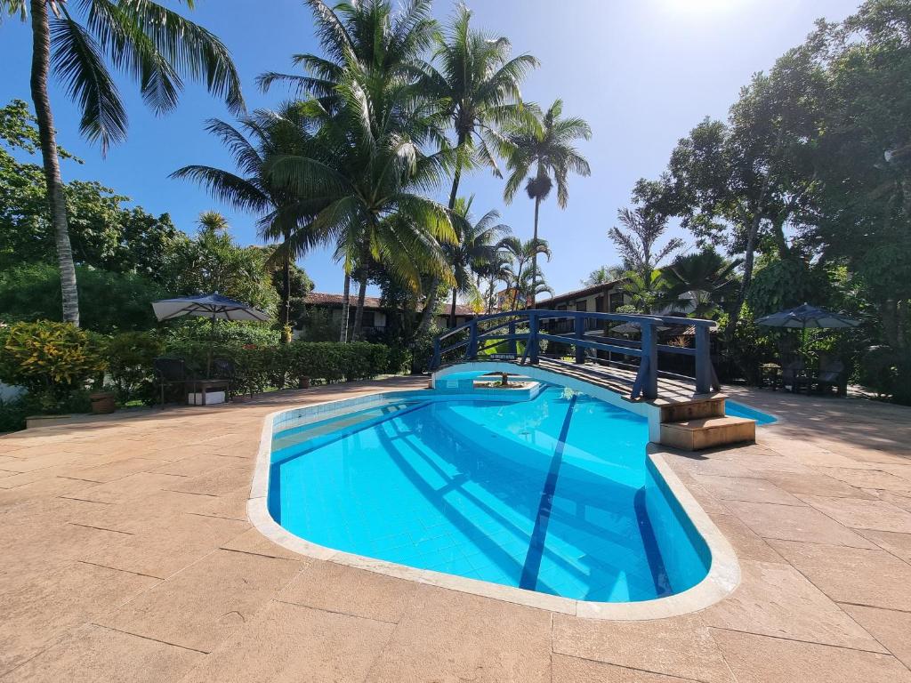 una piscina en un complejo con palmeras en Solar das Orquídeas, en Porto Seguro