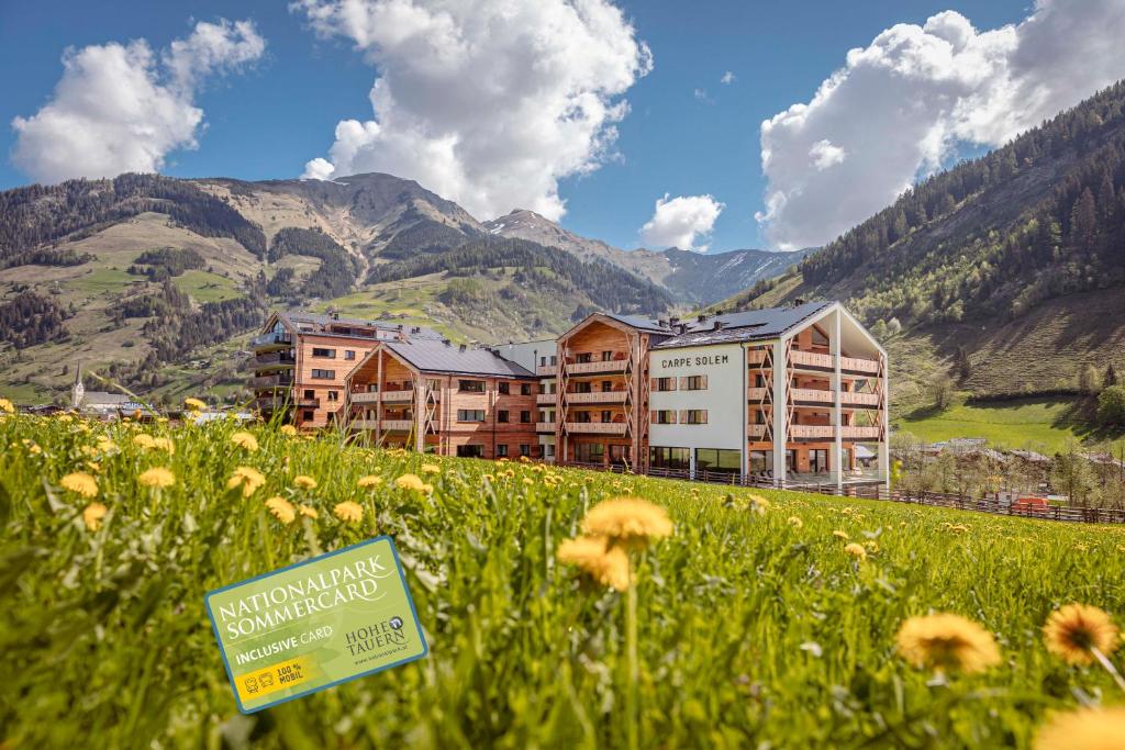 um hotel num campo de flores com montanhas ao fundo em Carpe Solem Rauris by ALPS RESORTS em Rauris