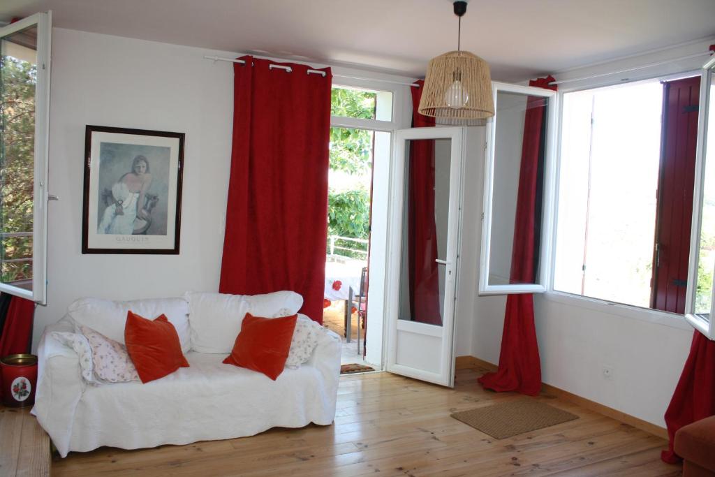 ein Wohnzimmer mit einem weißen Sofa und roten Vorhängen in der Unterkunft À l'ombre du mûrier in Blauvac