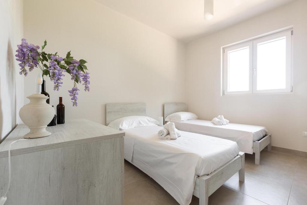 sypialnia z 2 łóżkami i wazonem z fioletowymi kwiatami w obiekcie Villa La Seta by Perle di Puglia w mieście San Vito dei Normanni