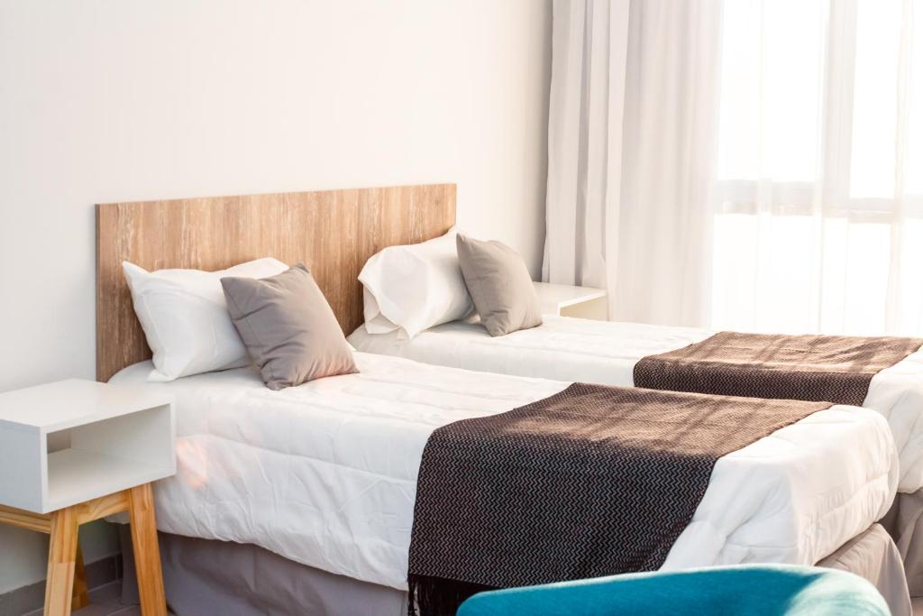 una camera d'albergo con due letti e una sedia di CQ MITRE a Puerto Madryn