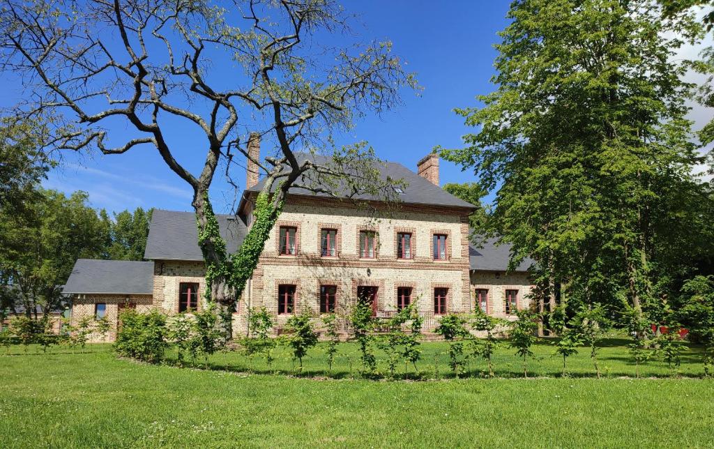 een oud stenen huis met een boom in de tuin bij Manoir de Daubeuf in Daubeuf-Serville