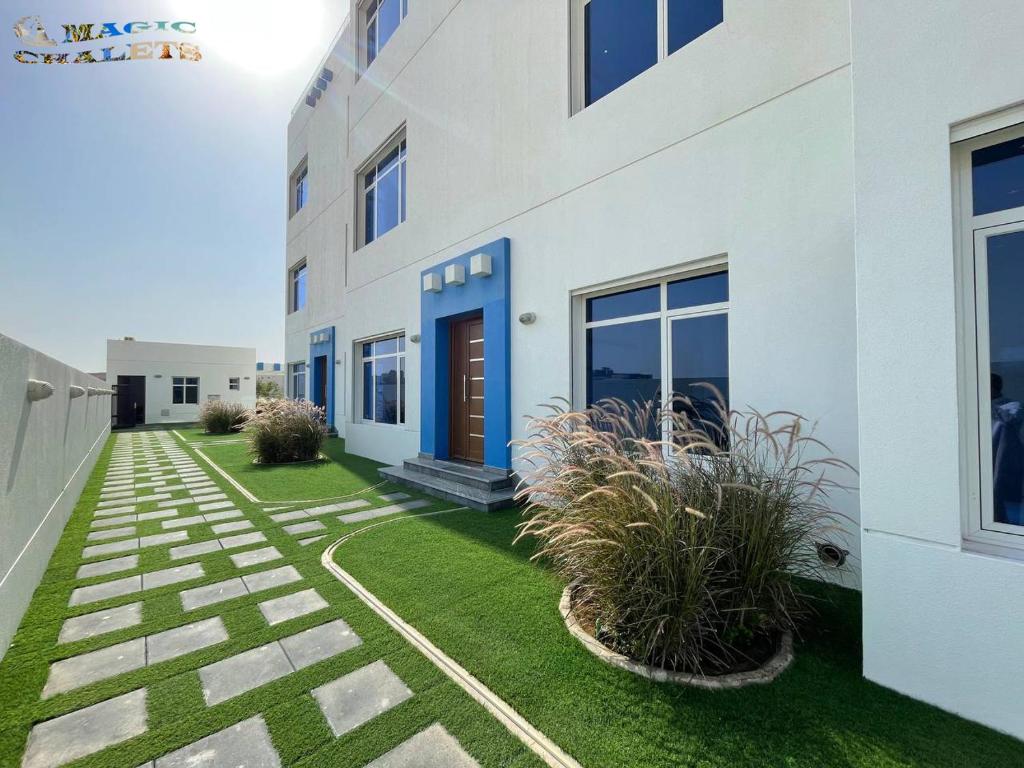 a white building with a yard with grass at شاليهات ماجيك in Al Khīrān