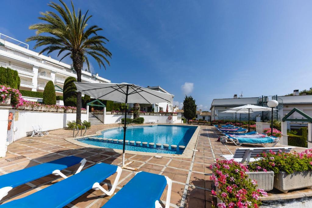 een zwembad in een hotel met stoelen en een parasol bij Bravissimo Vil·les Brusi A S'Agaró in S'Agaro