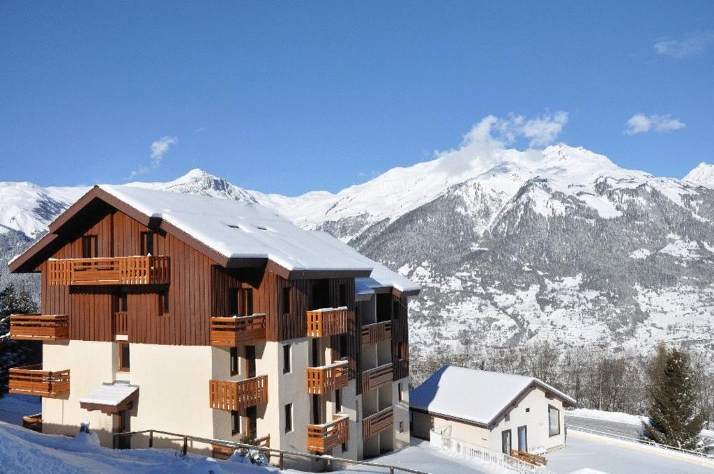 a building in the snow with mountains in the background at Résidence La Marmottane in Aime