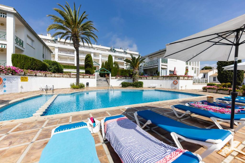 a swimming pool with lounge chairs and an umbrella at Bravissimo Vil·les Brusi B S'Agaró in S'Agaro