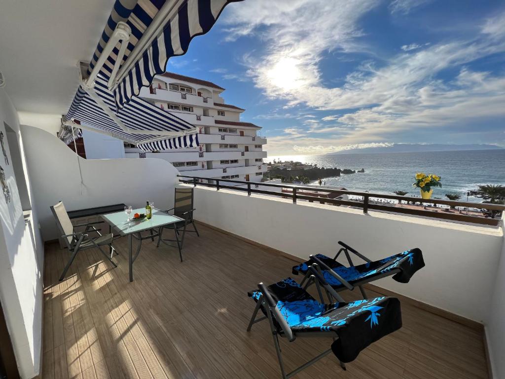 balkon ze stołem i krzesłami oraz oceanem w obiekcie Teneryfa -apartament z cudownym widokiem na ocean. w mieście Puerto de Santiago