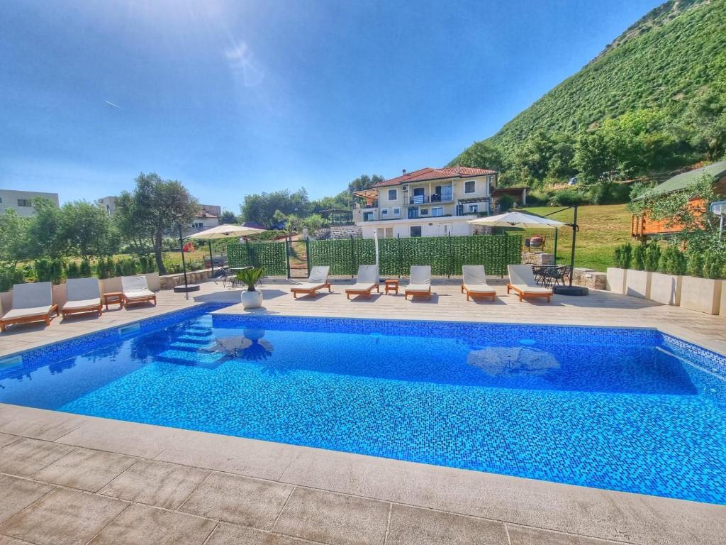 een zwembad met stoelen en een huis op de achtergrond bij Apartments Blazevic in Herceg-Novi